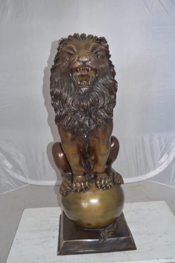Pair of lions standing on balls, bronze statues -  Size: 14"L x 16"W x 38"H.