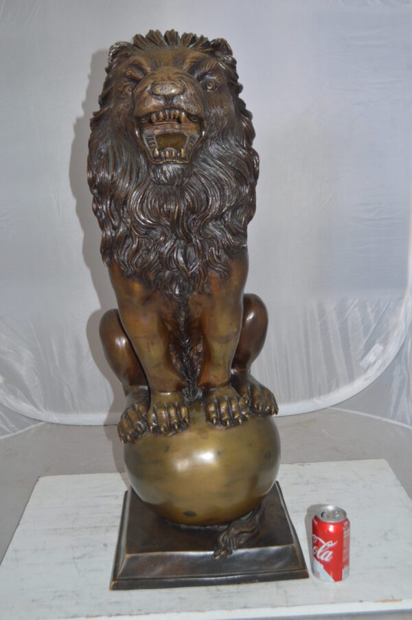 Pair of lions standing on balls, bronze statues -  Size: 14"L x 16"W x 38"H.