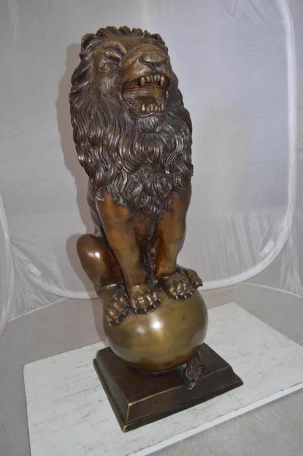 Pair of lions standing on balls, bronze statues -  Size: 14"L x 16"W x 38"H.