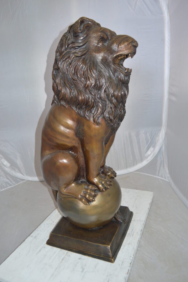 Pair of lions standing on balls, bronze statues -  Size: 14"L x 16"W x 38"H.