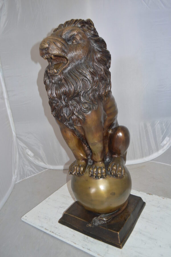 Pair of lions standing on balls, bronze statues -  Size: 14"L x 16"W x 38"H.