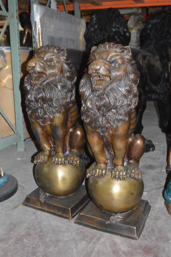 Pair of lions standing on balls, bronze statues -  Size: 14"L x 16"W x 38"H.