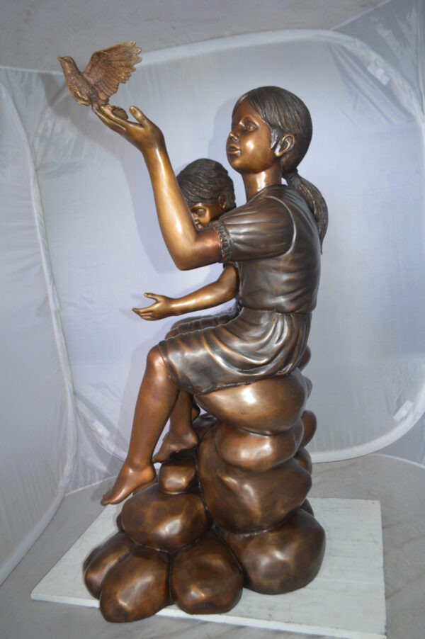 Two Kids on Rocks with a Bird Bronze Statue -  Size: 36"L x 30"W x 44"H.