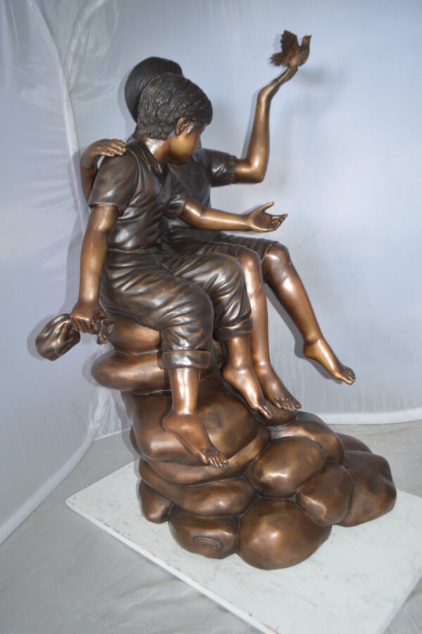 Two Kids on Rocks with a Bird Bronze Statue -  Size: 36"L x 30"W x 44"H.