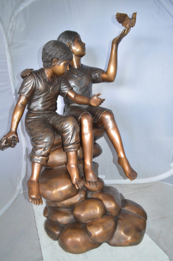 Two Kids on Rocks with a Bird Bronze Statue -  Size: 36"L x 30"W x 44"H.