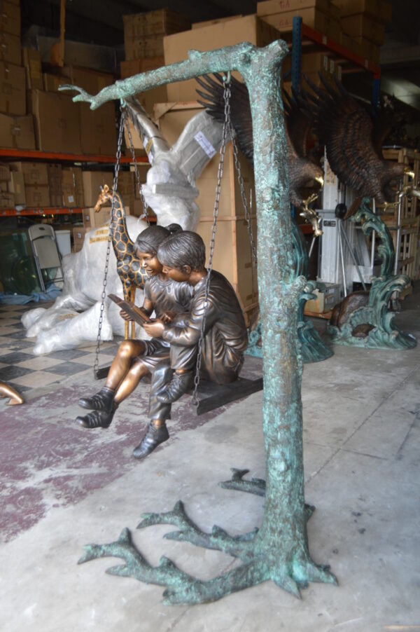 Kids on Swing Set Reading a Book Life Size Bronze Statue -  50"L x 40"W x 70"H.