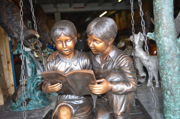 Kids on Swing Set Reading a Book Life Size Bronze Statue -  50"L x 40"W x 70"H.