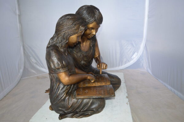 Two Girls Reading a Book Bronze Statue -  Size: 33"L x 21"W x 23"H.