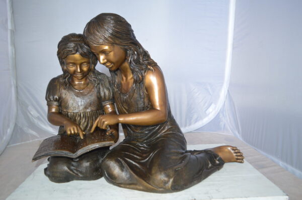 Two Girls Reading a Book Bronze Statue -  Size: 33"L x 21"W x 23"H.