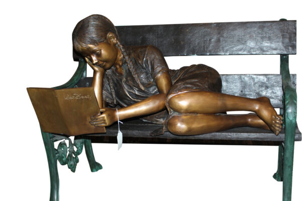 Girl laying on a bench reading a book Bronze Statue -  Size: 27"L x 39"W x 32"H