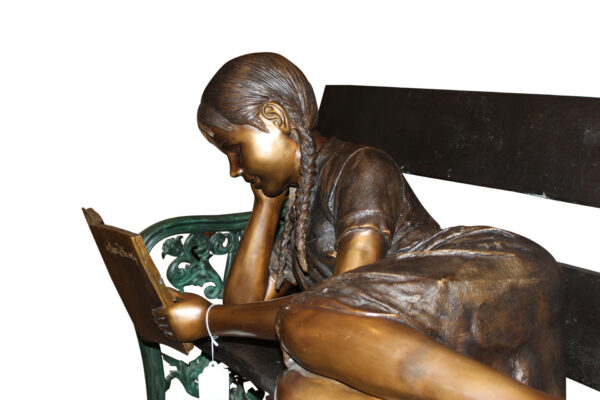 Girl laying on a bench reading a book Bronze Statue -  Size: 27"L x 39"W x 32"H