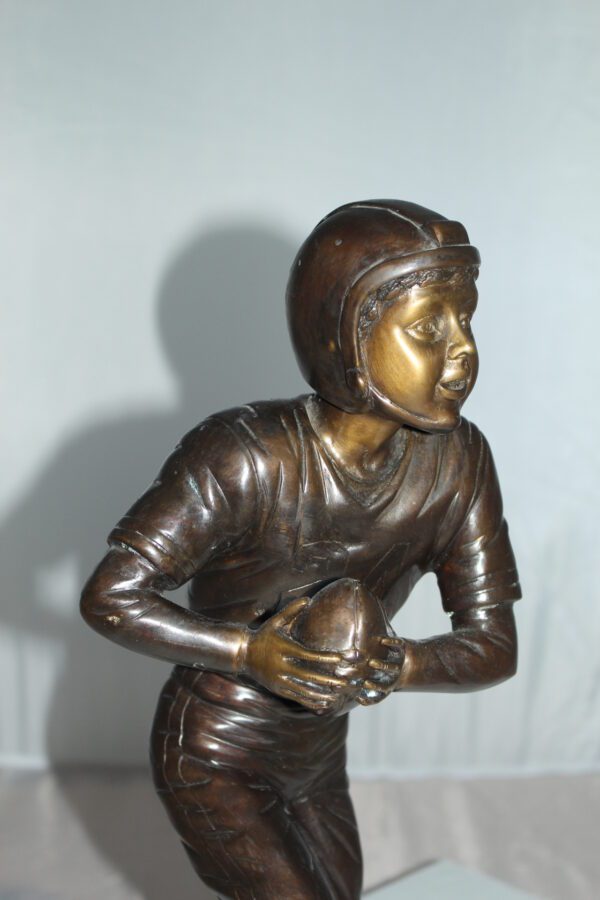 Boy playing football Bronze Statue -  Size: 10"L x 8"W x 20"H.