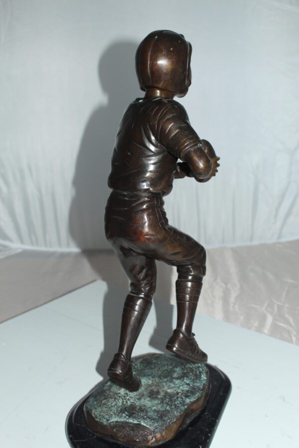 Boy playing football Bronze Statue -  Size: 10"L x 8"W x 20"H.