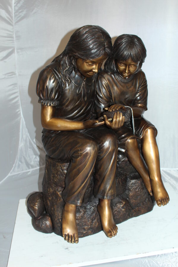 Two kids holding a bird Bronze Statue -  Size: 18"L x 26"W x 34"H.