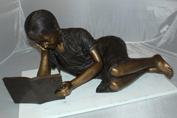 Girl laying reading a book Bronze Statue -  Size: 36"L x 17"W x 18"H.