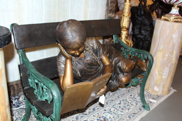 Girl laying on a bench reading a book Bronze Statue -  Size: 27"L x 39"W x 32"H