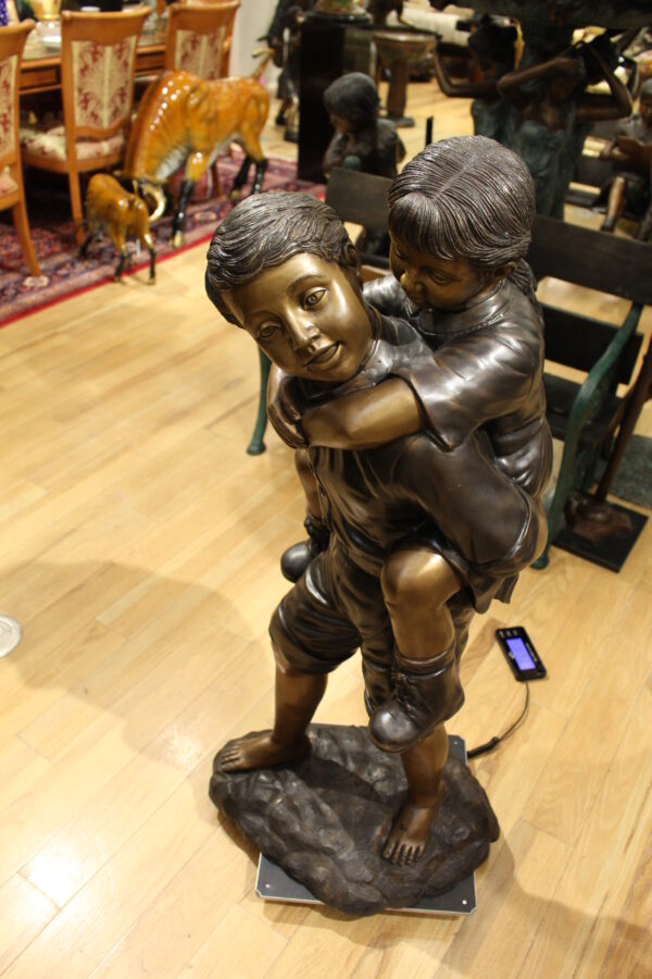 Boy Giving Girl Piggyback Ride Bronze Statue -  Size: 23"L x 16"W x 46"H.