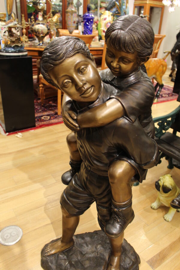 Boy Giving Girl Piggyback Ride Bronze Statue -  Size: 23"L x 16"W x 46"H.