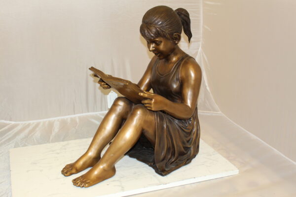 Girl Sitting and Reading a Book Bronze Statue -  Size: 23"L x 15"W x 24"H.