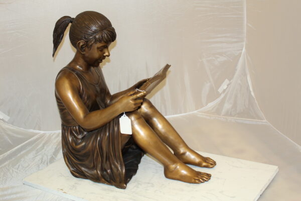 Girl Sitting and Reading a Book Bronze Statue -  Size: 23"L x 15"W x 24"H.