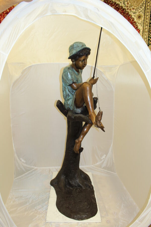 Boy Sitting on a Tree and Fishing Bronze Statue -  Size: 36"L x 21"W x 37"H.