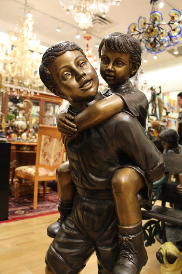 Boy Giving Girl Piggyback Ride Bronze Statue -  Size: 23"L x 16"W x 46"H.