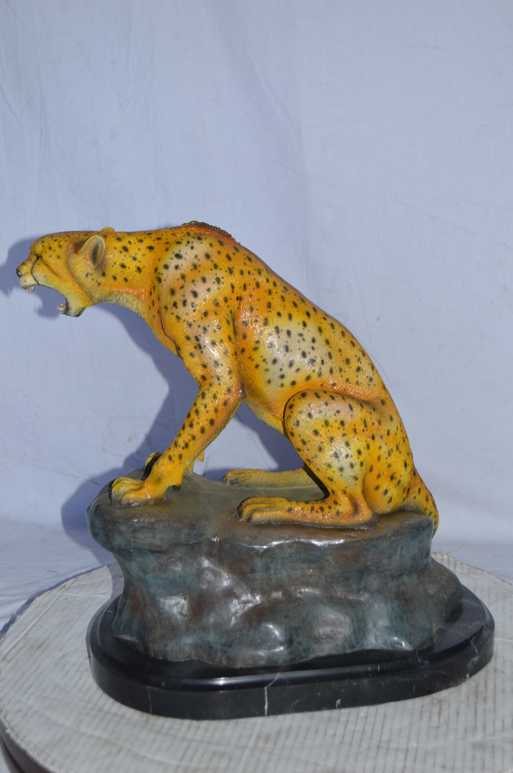 Cheetah sitting on a rock growling bronze statue - Size: 18L x 12